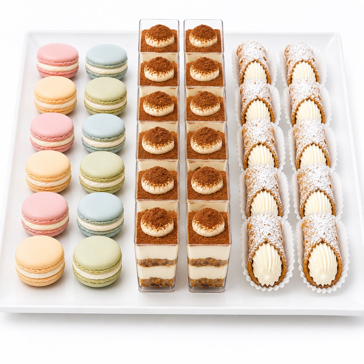 Coffret Mignardises Dcake : macarons colorés, tiramisus en verrine et cannolis sur plateau blanc